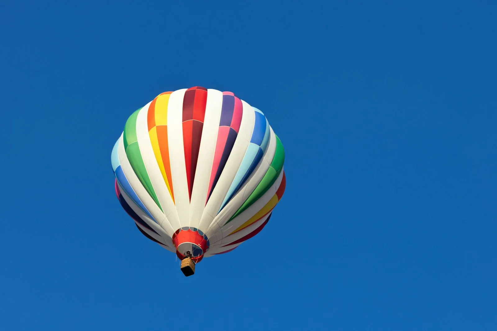 A colorful hot air balloon flying through a blue sky